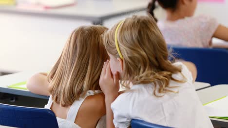 Schulmädchen-Flüstert-Ihrer-Freundin-Im-Klassenzimmer-Ins-Ohr