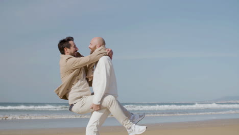 happy homosexual man jumping into partner's arms and kissing him on the beach