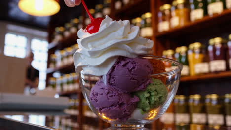 preparing a colorful ice cream sundae with whipped cream and a cherry