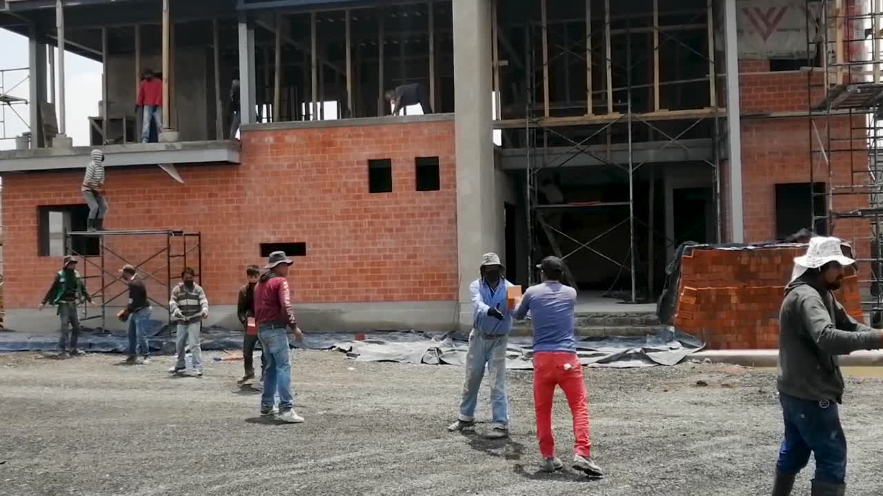 Shot of workers forming a human chain to unload material from the maneuvering yard to the second floor, which will be used for the interior construction of the developed project in Tepotzotán