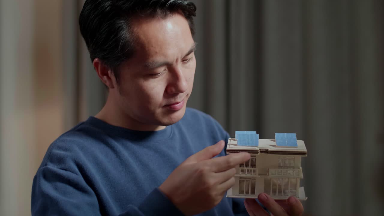 태양 전지 패널 을 가진 모형 집 을 조사 하는 사람