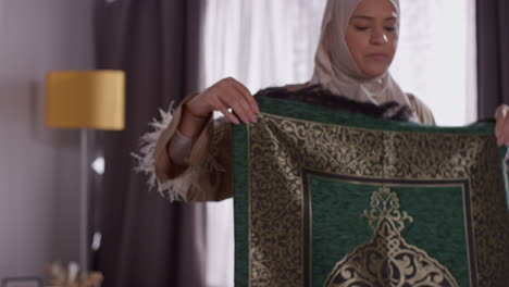 muslim woman wearing hijab at home laying down prayer mat on floor 3