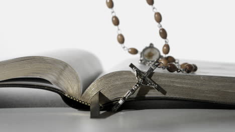 Rosary-beads-falling-onto-open-bible-on-white-background-close-up