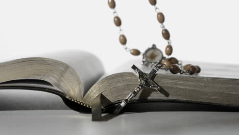 cuentas de rosario cayendo sobre la biblia abierta en fondo blanco de cerca