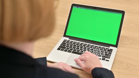 rear view of businesswoman scrolling laptop with chroma screen
