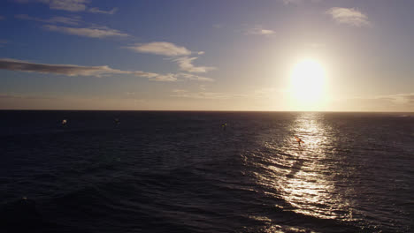 kite-boarders surf en el reflejo de la puesta de sol en el océano pacífico en hawai imágenes aéreas