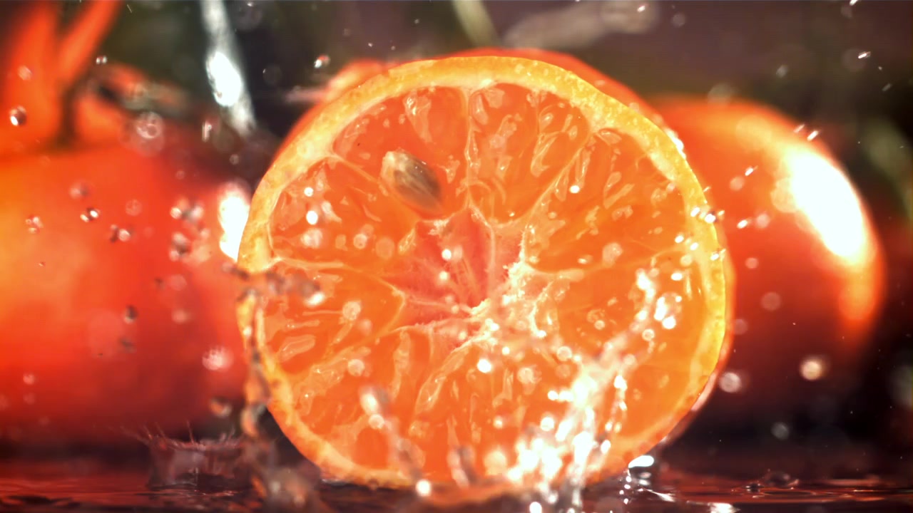 Levende orange halvdel oversprøjtet med vand i slowmotion