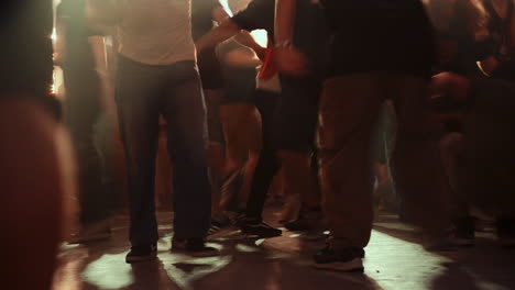 Dynamic dance floor scene with blurred feet moving energetically in warm ambient lighting