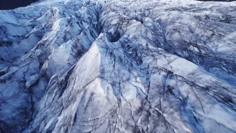 Aerial:-Close-flyover-of-glaciers-serpentine-path-with-deep-crevasses-and-jagged-ice-formations,-evidence-of-climate-change-impact-on-the-constant-movement-and-transformation-of-this-natural-wonder