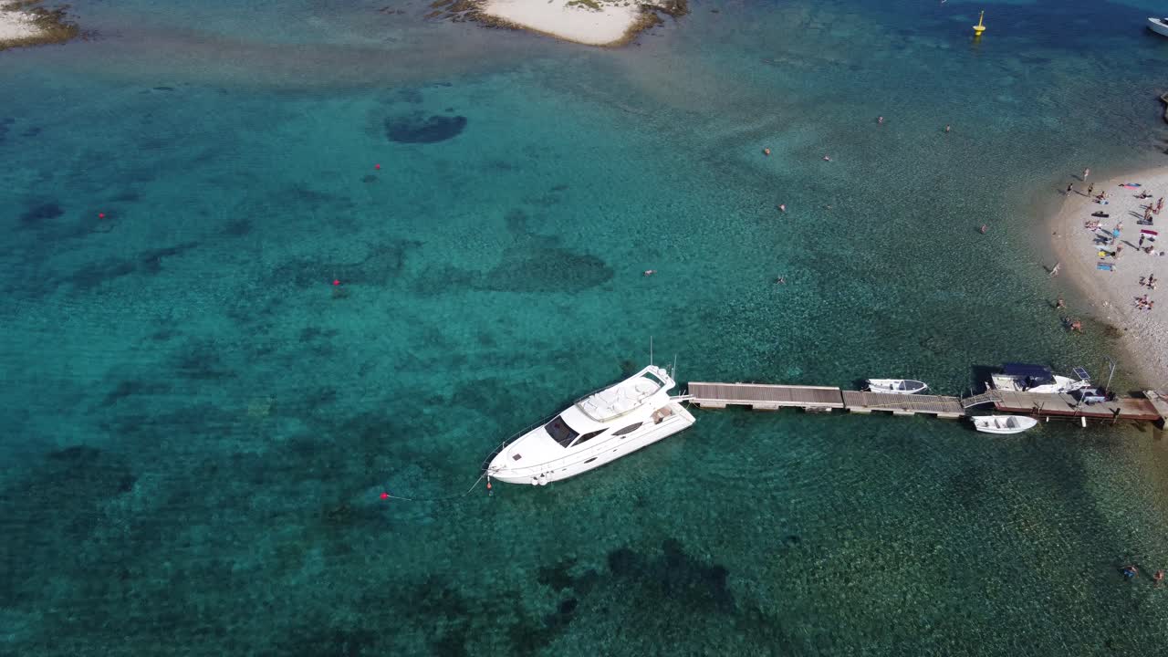 barco de velocidad de yate atracado en el muelle de la playa en la laguna azul de budikovac, croacia con personas nadando