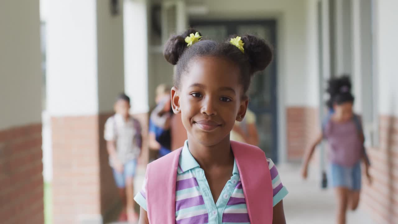 Video of happy african american girl standing at school corridor