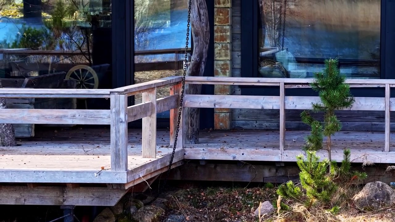 Water seeping through dry grass and rocky embankment below wooden deck in natural setting