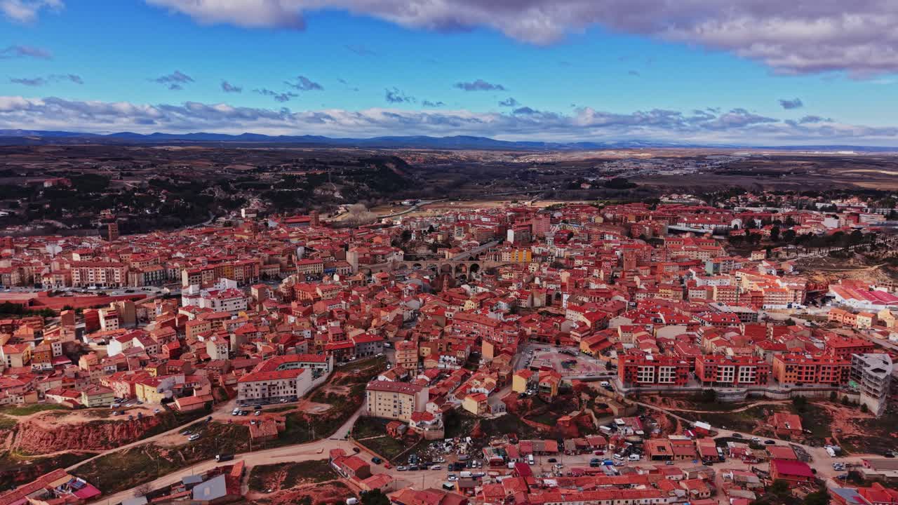 Udsigt over en by i Spanien med røde tage og bjerge i baggrunden