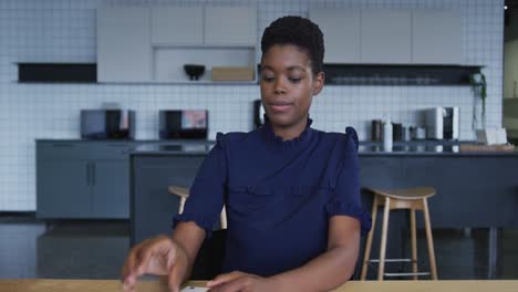 African-american-businesswoman-having-video-chat-going-through-paperwork-and-listening-in-workplace-