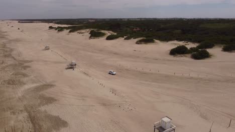 Antena:-Vehículos-De-4-Ruedas-Conduciendo-Y-Saliendo-De-La-Playa-De-Arena-Durante-El-Día-Soleado---Mar-De-Las-Pampas,-Argentina