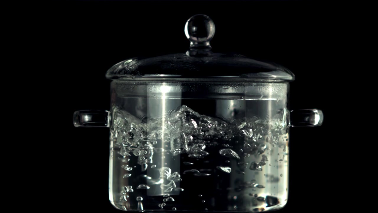 Pentola di vetro trasparente con acqua che bolle su sfondo nero