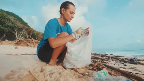joven mujer caucásica voluntaria se sienta en el océano y limpia la playa de basura