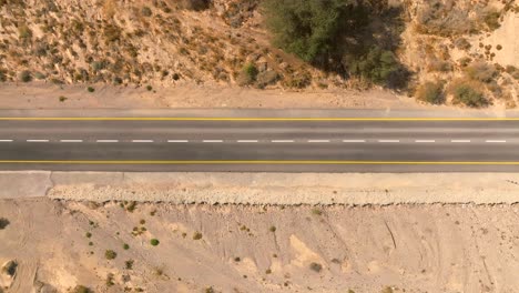 Car-zooming-by-heading-north-on-a-Desert-highway-with-cloudy-blue-sky