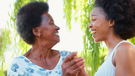 Mehrgenerationenfamilie-Mit-älterer-Mutter-Und-Erwachsener-Tochter,-Die-Gemeinsam-Im-Garten-Lachen