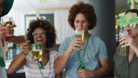 un grupo diverso de amigos felices celebrando el día de san patricio bebiendo cervezas haciendo un brindis en un bar