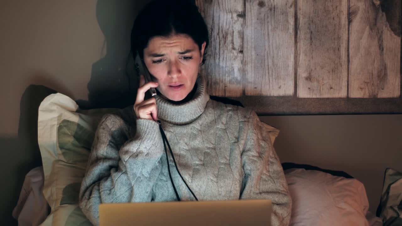 Freelancer woman arguing on phone while looking at laptop, at home office