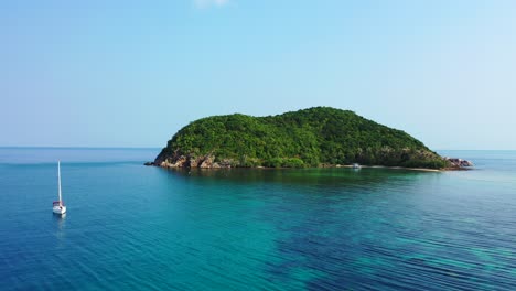 Luxury-modern-sailing-boat-sailing-around-the-small-uninhabited-island-in-peaceful-ocean