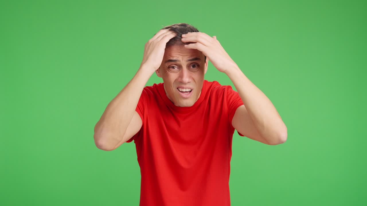 Man expressing worry about hair loss on green screen