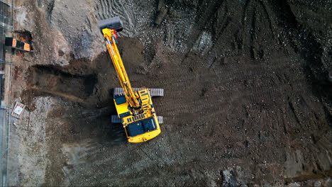 Vista-Aérea-Estática-De-Arriba-Hacia-Abajo-De-La-Excavadora-Girando-Sobre-Orugas-En-El-Sitio-De-Construcción