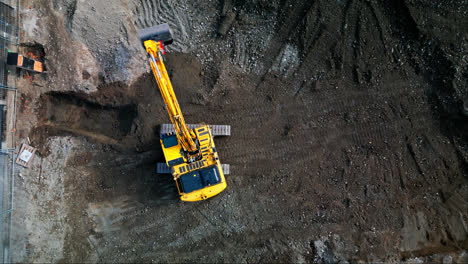 vista aérea estática de arriba hacia abajo de una excavadora que gira sobre vías en un sitio de construcción