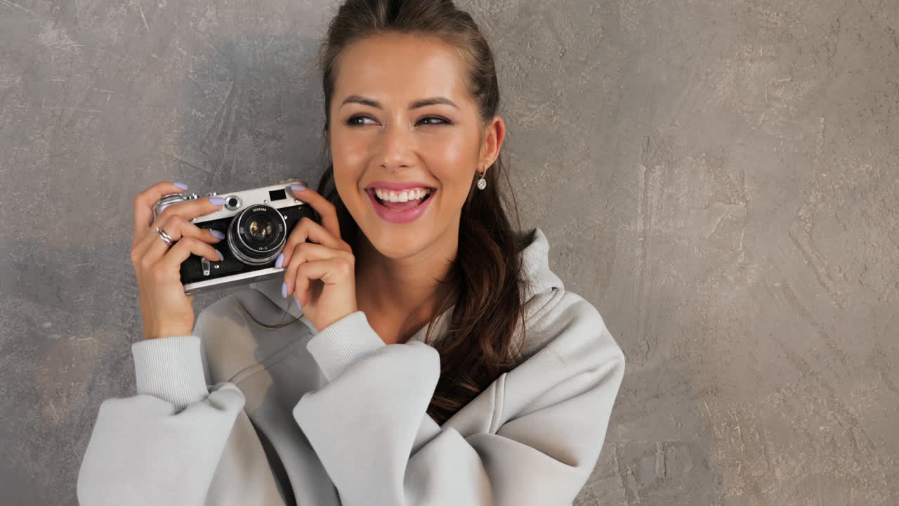 Donna sorridente che scatta una foto con una macchina fotografica vintage