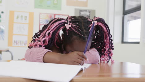 in classroom, african american girl resting head on desk, looking tired, at school