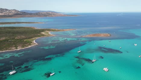 barcos en el mar azul turquesa en la pelosa cerca del parque nacional de asinara, cerdeña, italia - antena 4k hacia atrás