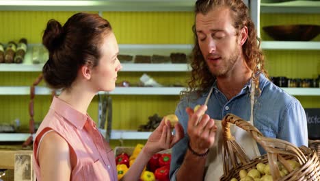 male staff assisting woman in selecting fresh vegetables