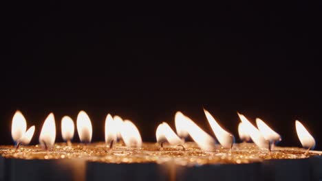 many lit candles with gold glitter on a dark background