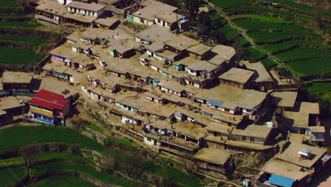 un pueblo en la esquina de la montaña, gente caminando, tejados de las casas, vista aérea
