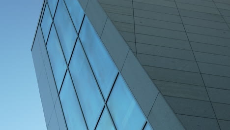ángulo abstracto de un edificio moderno con una fachada de vidrio geométrica contra un cielo despejado