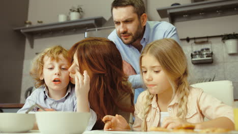 Familie-Beim-Frühstücken-Und-Mit-Einem-Tablet-In-Der-Küche