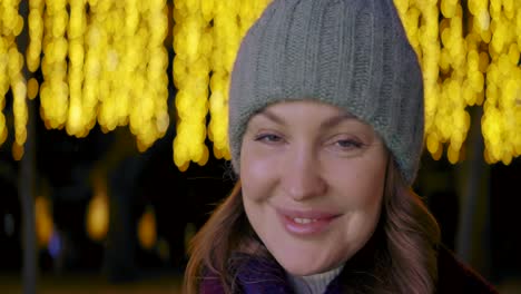 woman smiling at night with christmas lights