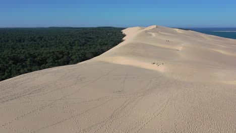 dune of pilat in the arcachon bassin france at cap ferret with a height of 110meters and people walking below, aerial flyover shot