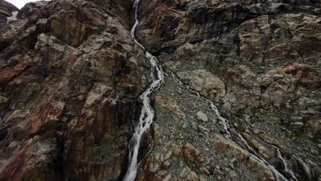 incredible drone flight over water and waterfall stream flowing at fellaria glacier in valmalenco of valtellina, italy