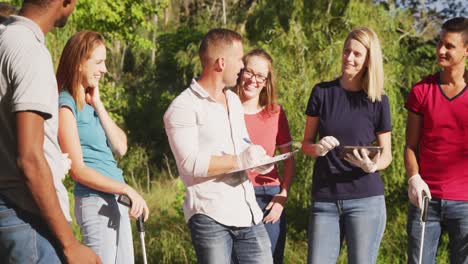 średni dorośli wolontariusze robią notatki i używają tabletu podczas dnia sprzątania rzeki