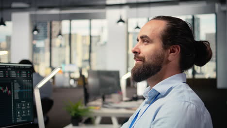 trader with smile on face in office looks upward, visualizing financial success