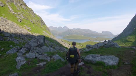 A-hiker-descends-toward-the-bottom-of-the-mountain-on-a-trail-through-large-rocks-in-a-valley