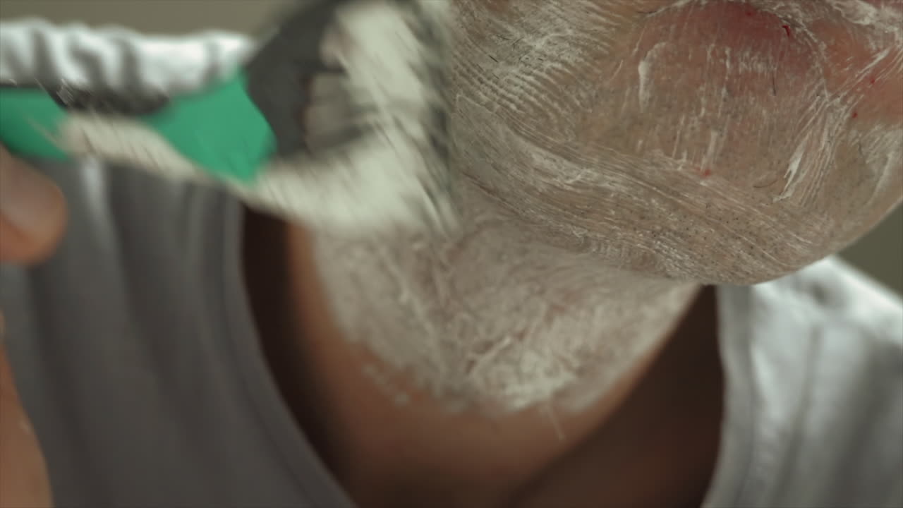 Close up of a man shaving his beard with a green and black razor