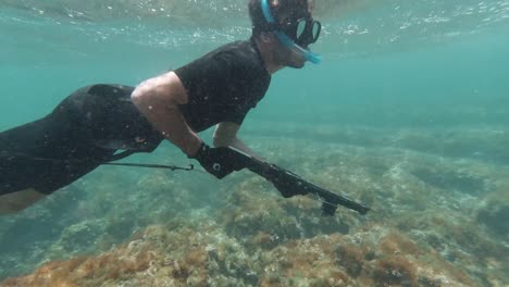 side shot of spearfisher snorkeling in the mediterranean sea in very shallow waters looking for fish