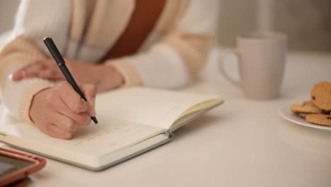 mujer, cuaderno y manos escribiendo en casa