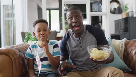 Video-De-Un-Feliz-Padre-E-Hijo-Afroamericanos-Sentados-En-El-Sofá-Y-Viendo-El-Partido-En-La-Televisión