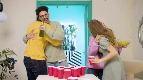 happy multiethnic young friends playing beer pong at home