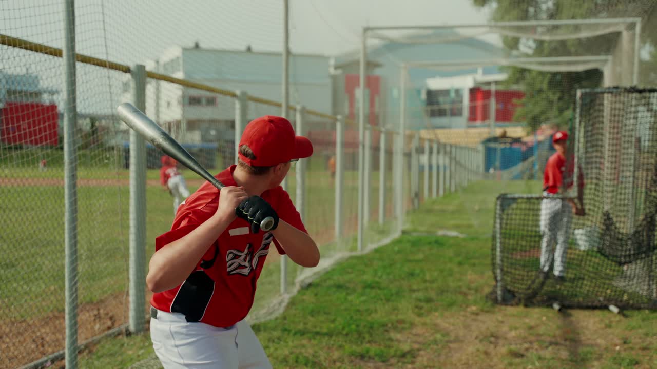 Giocatori di baseball che si allenano a battere in una gabbia di battuta
