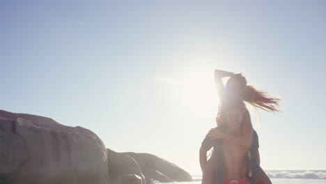 attractive man giving girlfriend piggyback couple enjoying nature  on the beach